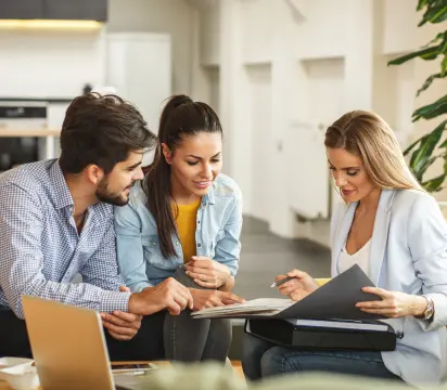 Três corretores de imóvel estudando estudando o portfólio de apartamentos da MRV.