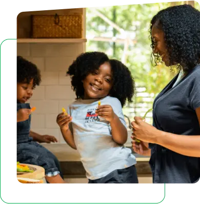 Mulher com duas crianças sorrindo dentro de uma cozinha 