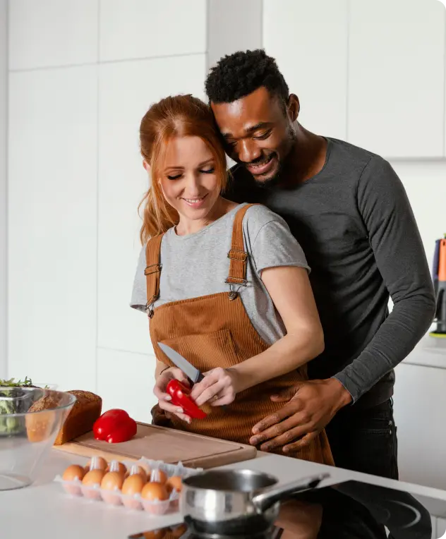 Casal preparando comida na cozinha do apartamento novo.