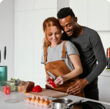 Casal preparando comida na cozinha do apartamento novo.