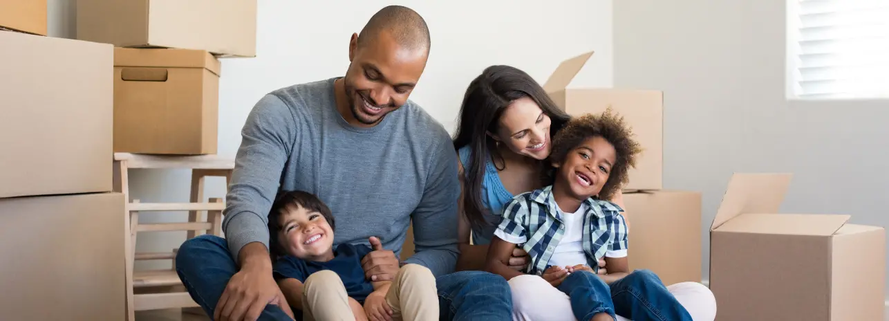 Família feliz em uma sala de apartamento cheia de caixas de mudanças