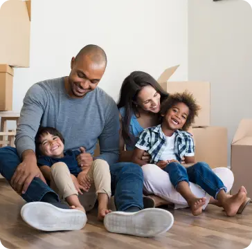 Família feliz em uma sala de apartamento cheia de caixas de mudanças